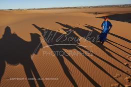 Image du Maroc Professionnelle de  L'ombre d'une caravane avec son guide et ses touristes au lever du soleil sur les dunes de sable du Sahara à Merzouga dans la région de Drâa-Tafilalet au Sud Est du Maroc, le long de ce que l'on appelle la route des mille kasbahs, Dimanche 5 mars 2017. De nombreux touristes visitent les dunes de Merzouga à l’aube pour contempler la beauté du lever du soleil sur les dunes de sable du Sahara. (Photo / Abdeljalil Bounhar 